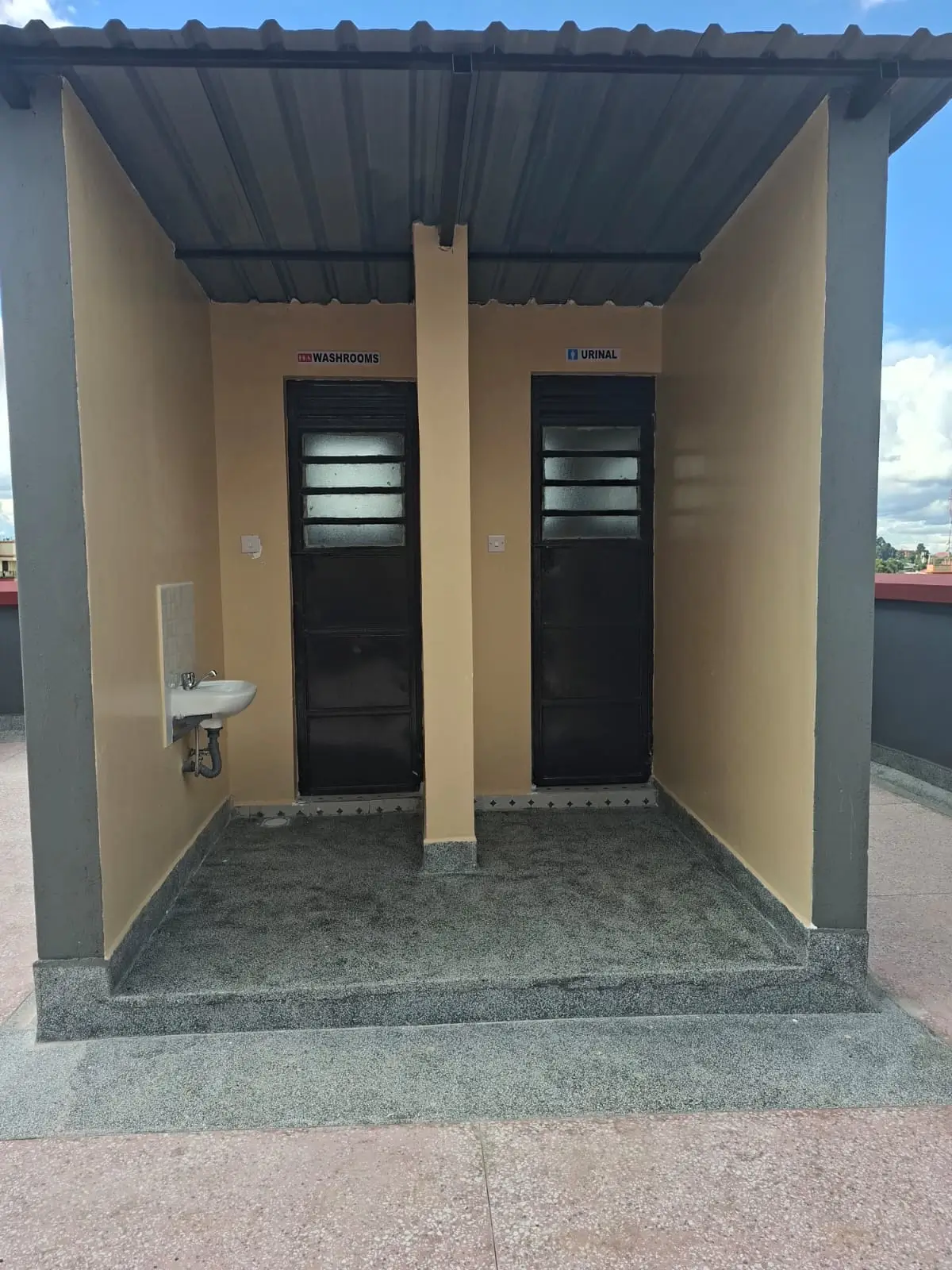 Dual bathroom cubicles with black doors and sink