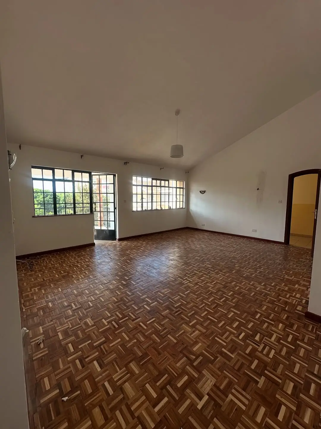 Spacious living room with herringbone wood flooring and natural light