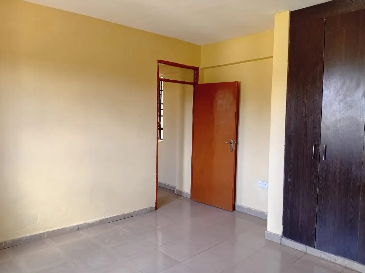Unfurnished bedroom with yellow walls and dark wooden wardrobe