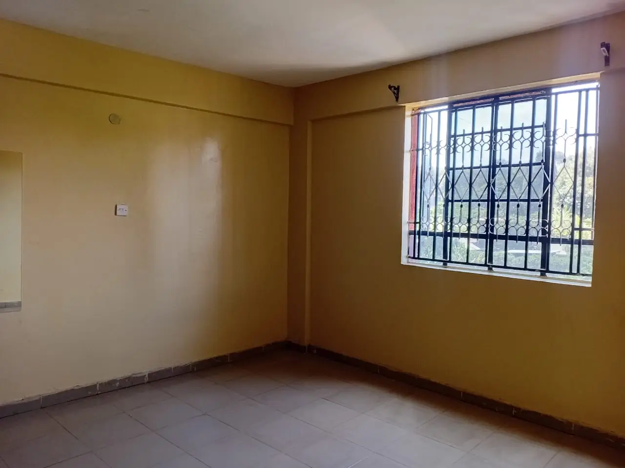 Empty bedroom with yellow walls and barred window