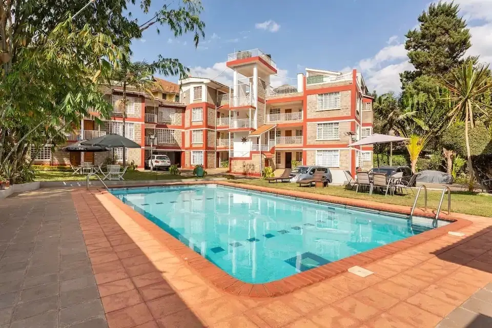 Rectangular swimming pool with terracotta deck and apartment building