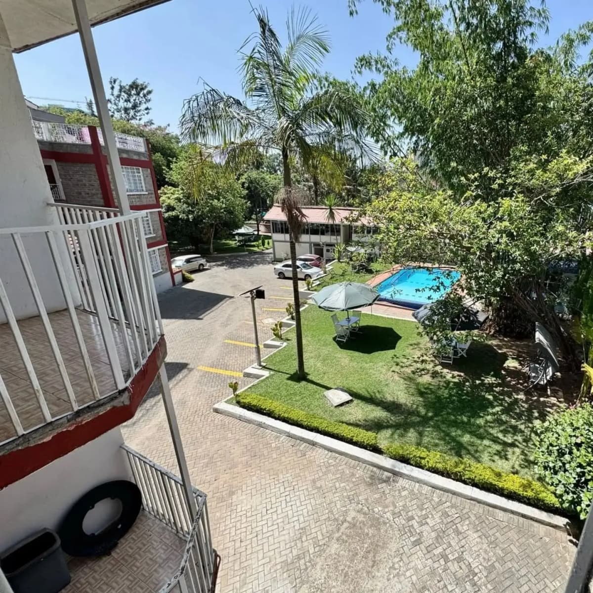 Compound grounds with pool, lawn, and palm trees visible
