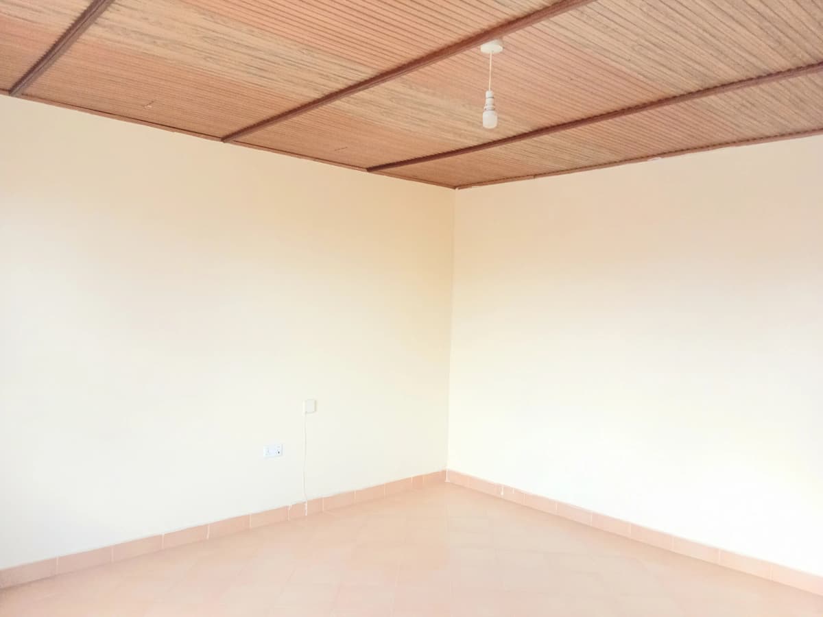 Empty bedroom with wooden ceiling and plain walls