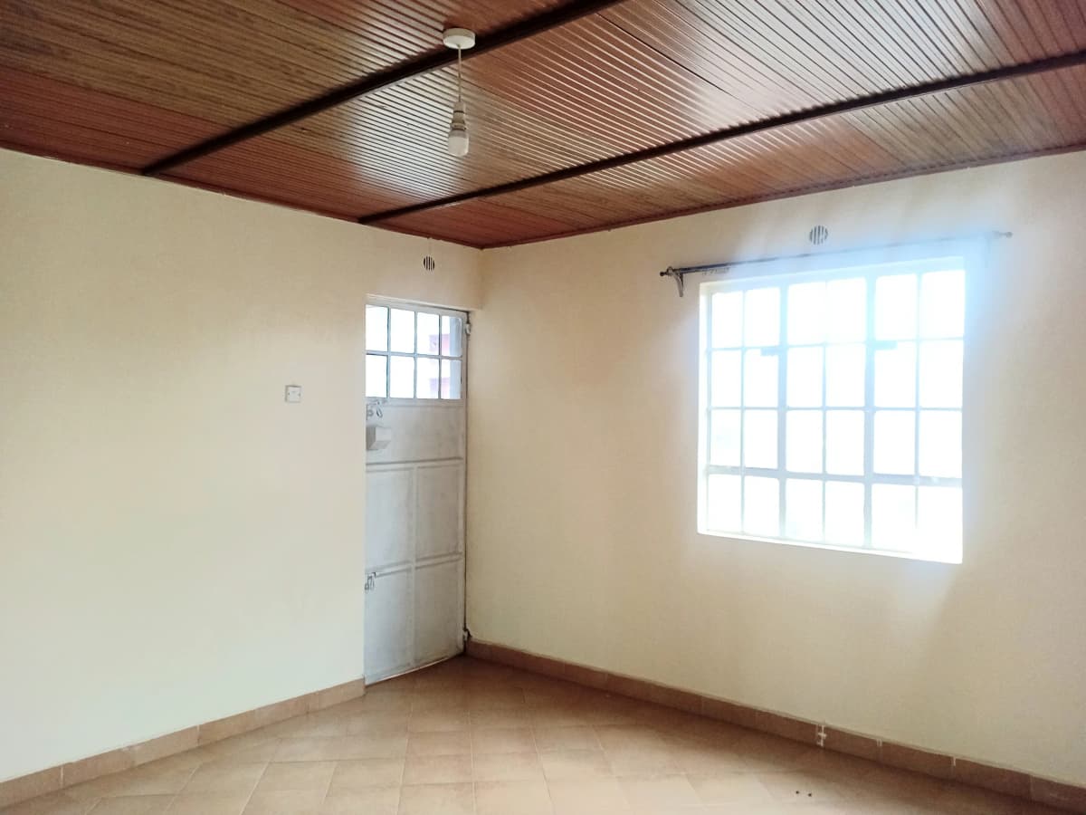 Empty bedroom with wooden ceiling and bright window light