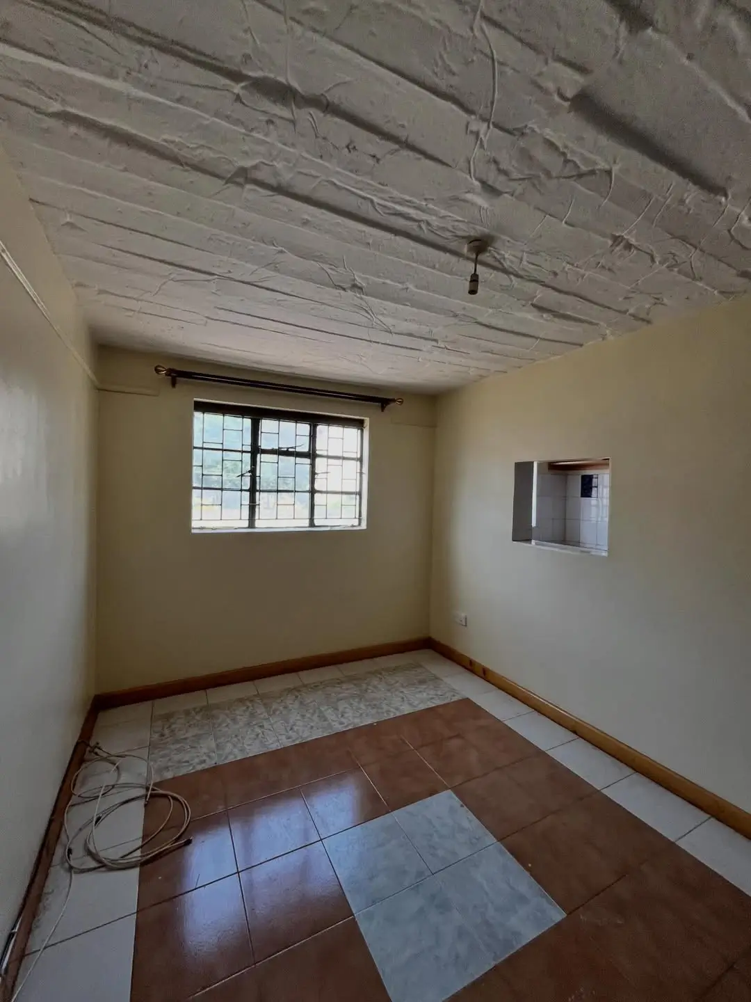 Bare bedroom with window, exposed ceiling, tile flooring