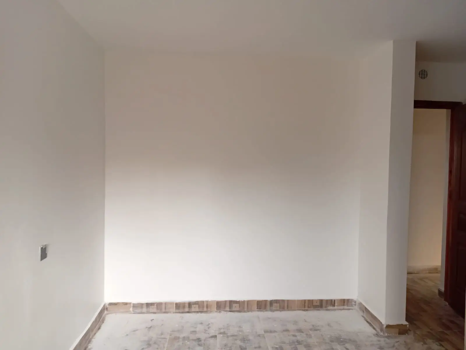 Empty bedroom with white walls and tiled flooring