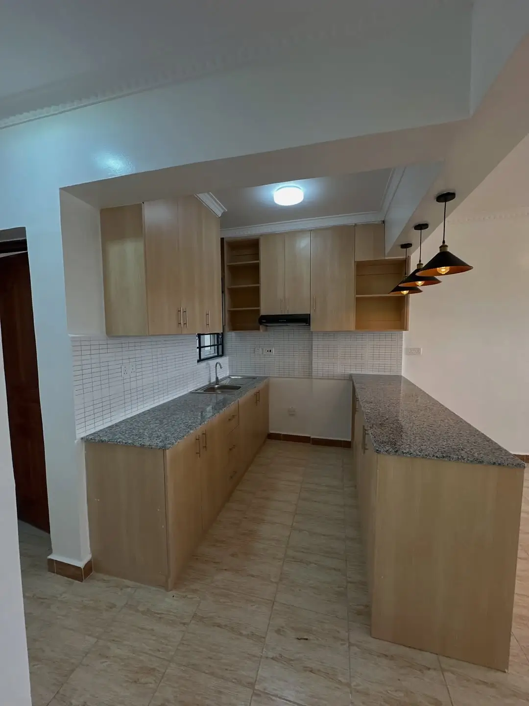 Modern kitchen with granite counters, white tile backsplash, pendant lighting