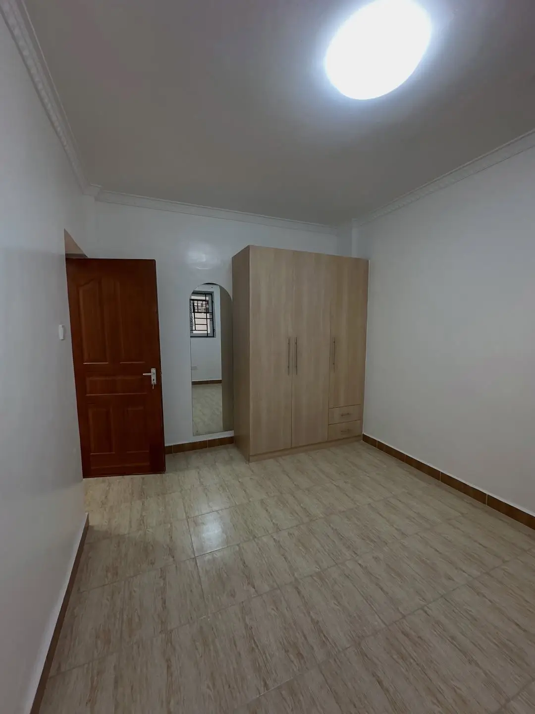 Spacious bedroom with wooden wardrobe and laminate flooring