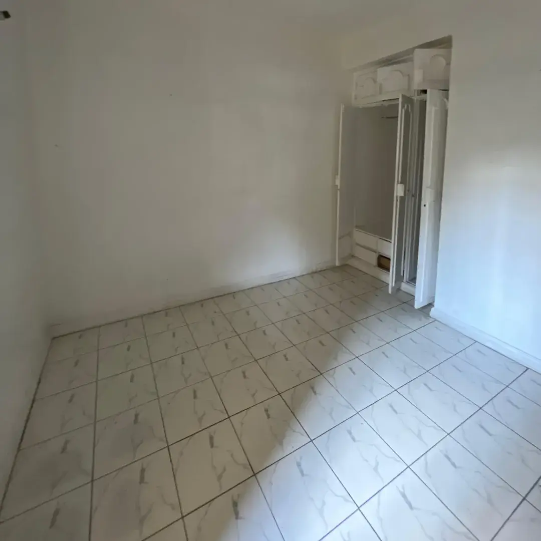 Empty bedroom with tiled flooring and built-in wardrobes