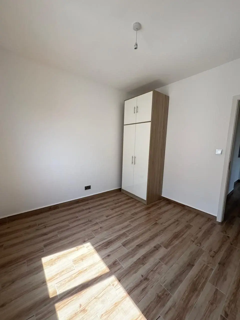 Spacious bedroom with wooden flooring and built-in wardrobe