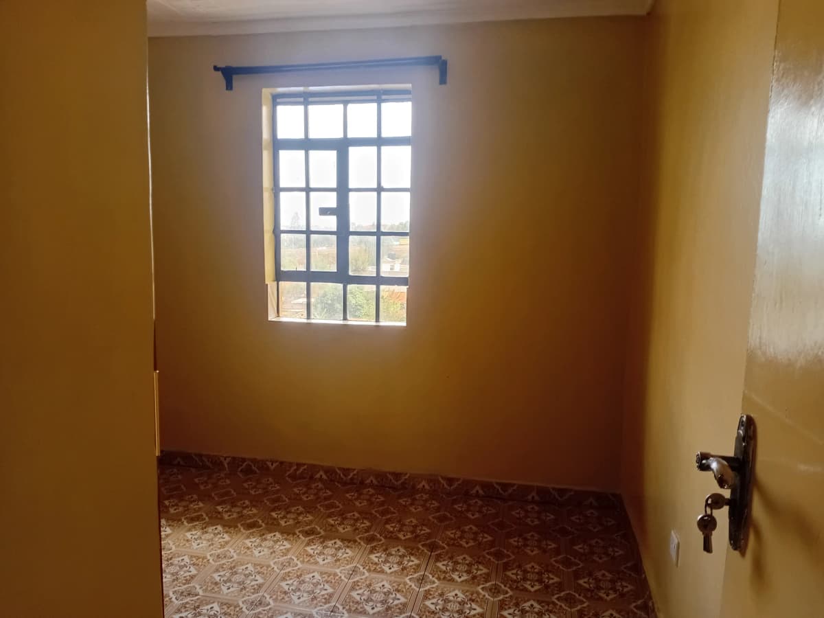 Unfurnished bedroom with barred window and terracotta tile floor